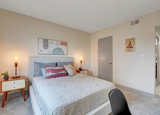 A bedroom with a bed, a chair, and a painting on the wall.