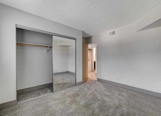 A room with a white wall and a grey carpet.