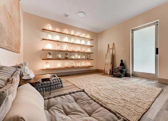 A living room with a couch, a rug, and a wall with lights on it.