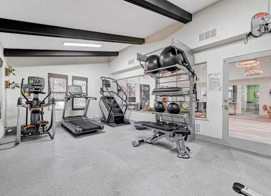 A gym with a variety of equipment including treadmills, weights, and exercise machines.
