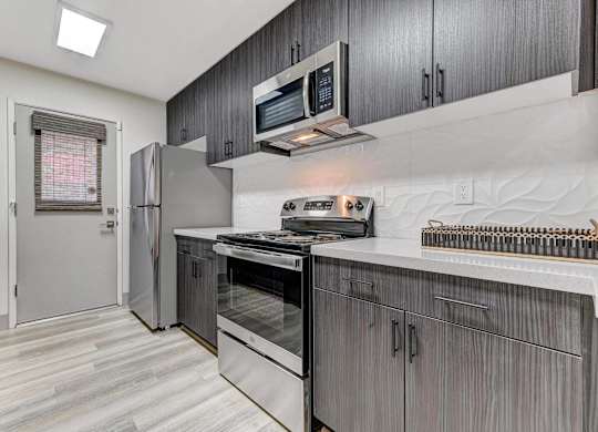 A modern kitchen with a stainless steel refrigerator and oven.