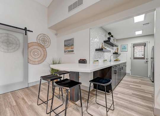 A kitchen with a white countertop and black barstools.