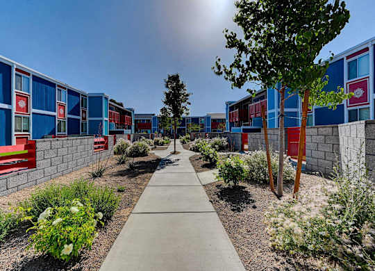 A walkway leads between a row of blue and red buildings.