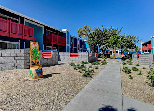 A colorful building with a red balcony and a yellow sign with a palm tree on it.