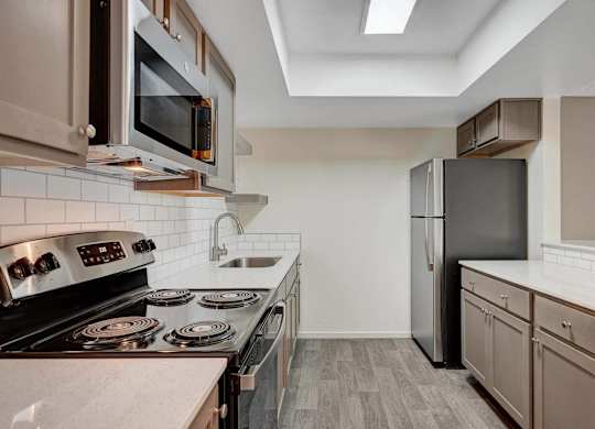 A kitchen with a black refrigerator and stove top oven.