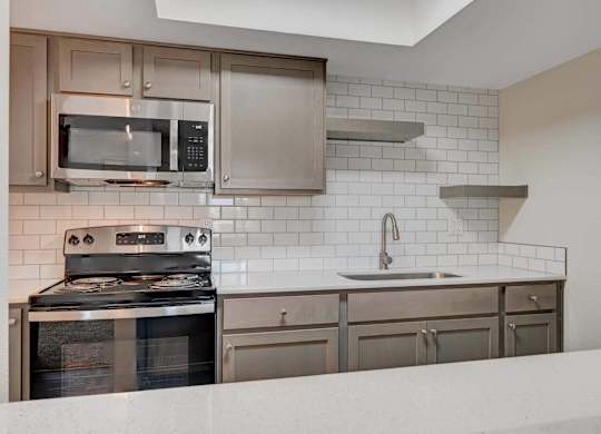 A modern kitchen with stainless steel appliances and white subway tiles.
