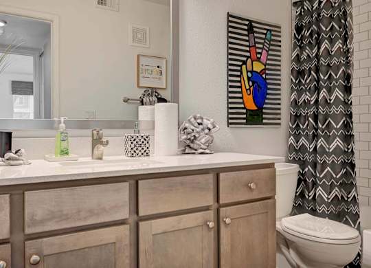 A bathroom with a toilet, sink, and a painting on the wall.