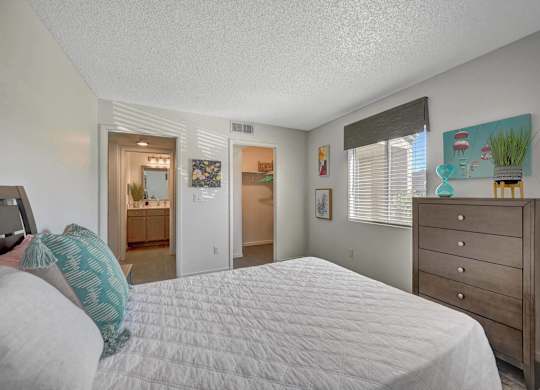 A bedroom with a bed, dresser, and a painting on the wall.