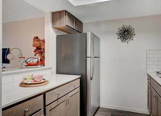 A kitchen with a refrigerator, countertop, and cabinets.
