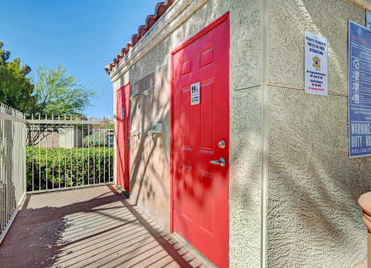 A red door is on the left side of a building with a sign on the right side.