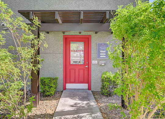 A red door with a sign that says "SOLSTICE" on it.