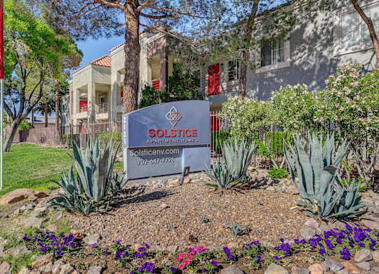 A sign for Solstice Apartments is in front of a building.