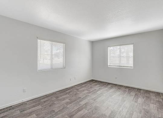A room with wooden flooring and two windows with blinds. at The 95 Apartments, Las Vegas, 89129
