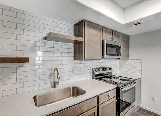 A kitchen with a stove, sink, and microwave. at The 95 Apartments, Las Vegas, NV