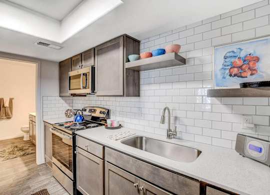 A modern kitchen with stainless steel appliances and a white tiled backsplash. at The 95 Apartments, Las Vegas, Nevada