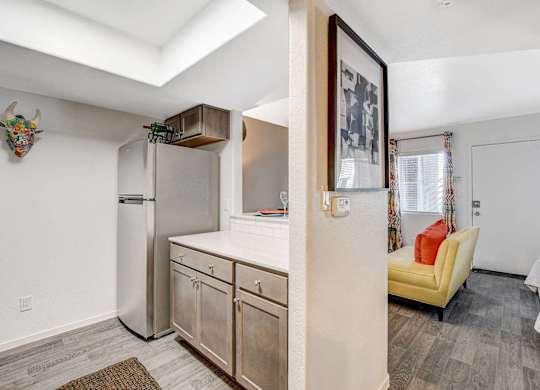 A kitchen with a refrigerator, cabinets, and a yellow chair. at The 95 Apartments, Las Vegas, NV