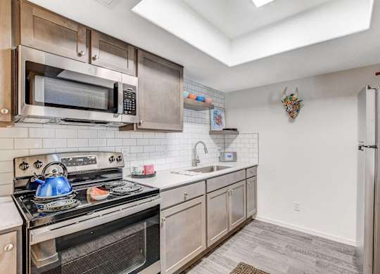 A kitchen with a stove, microwave, and refrigerator. at The 95 Apartments, Las Vegas
