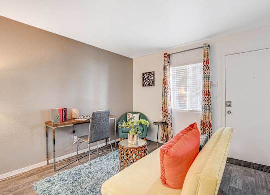 A room with a yellow couch and a desk with a chair. at The 95 Apartments, Nevada