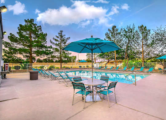 A poolside area with chairs and umbrellas. at The 95 Apartments, Las Vegas, NV, 89129