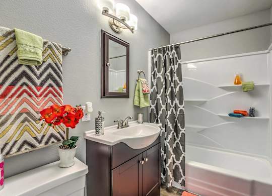 A bathroom with a white tub and a sink with a mirror above it.