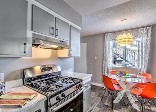 A modern kitchen with a stove top oven and a dining table with chairs.