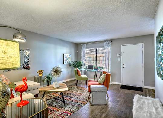 A living room with a white couch, a red chair, and a white ottoman.