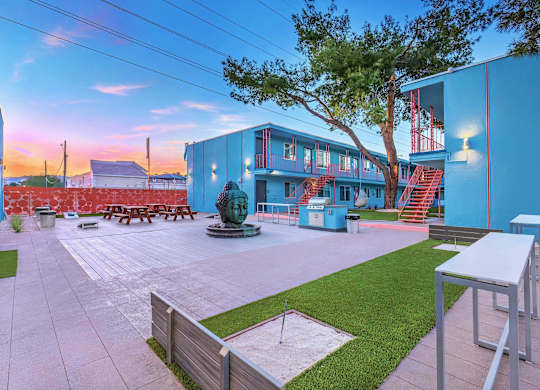 A blue building with a red staircase and a statue in front.