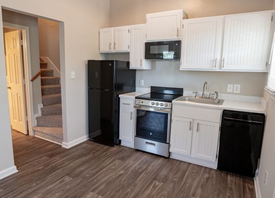 Spacious kitchen with white cabinetry,  black energy efficient appliances and plank style flooring