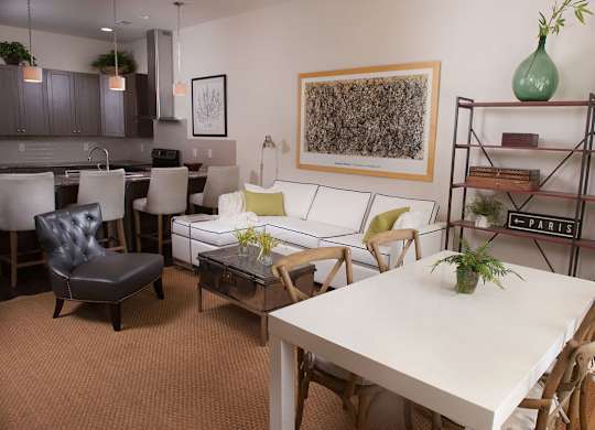 A living room with a white couch and a white dining table.