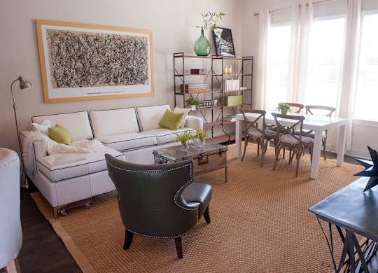 A living room with a white couch, a green chair, and a painting on the wall.