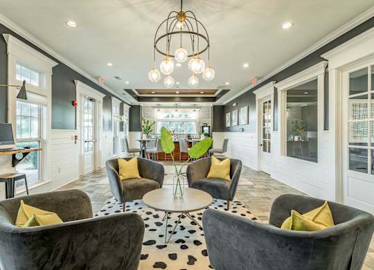 A living room with grey chairs and a round table with a vase of flowers on it.