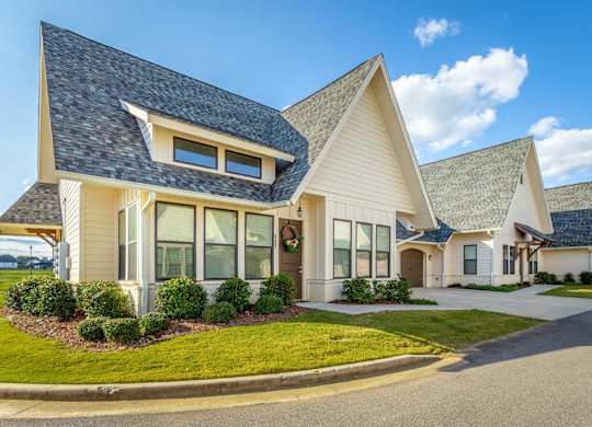 A modern house with a curved roof and a front yard.