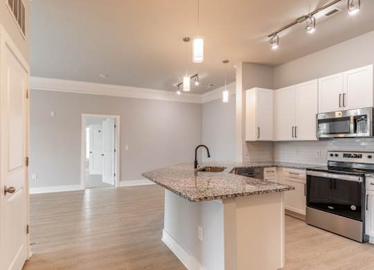 A kitchen with a granite countertop and stainless steel appliances.