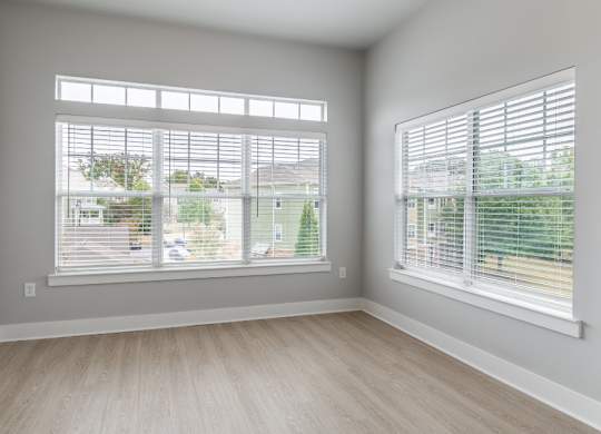 A room with two windows covered in white blinds.