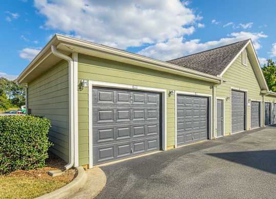 A green house with grey garage doors.