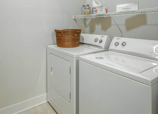 A white washing machine and dryer with a basket on top of the dryer.