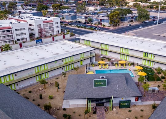 Aerial view of Las Vegas fusion apartments 89119 with bright green doors around clubhouse and community pool in desert landscape