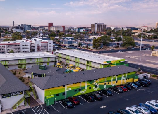 Aerial view of four Las Vegas Fusion apartment complex in a square around amenities house and community pool in desert landscape.