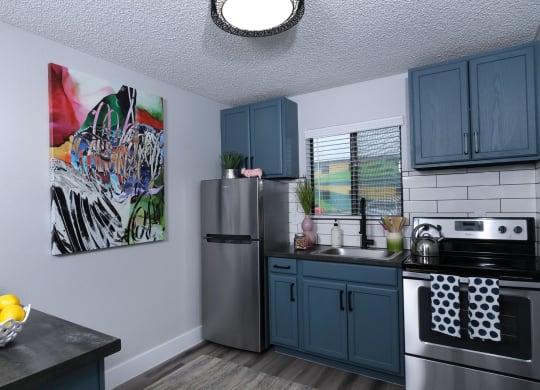 Fusion Las Vegas studios for rent in Vegas. Apartment kitchen with colorful modern painting, large window above the sink, and island with bowl of lemons.
