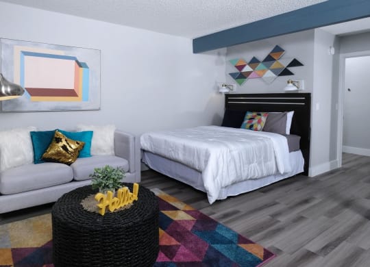 Fusion Las Vegas studio apartments Las Vegas with large bed, geometric wall hangings and paintings, and small couch with modern standing reading lamp.