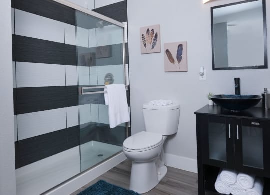 Fusion Las Vegas apartment bathroom with basin sink and black and modern black and white tiled shower with sliding glass door.