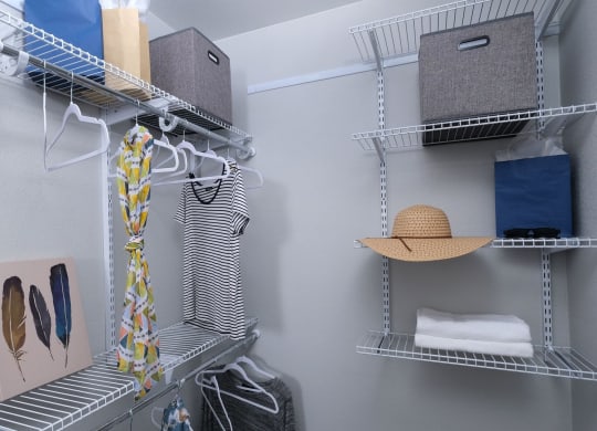 Fusion Las Vegas apartment closet with grey and blue cloth storage boxes, towels, and hangers on built in wire shelving.