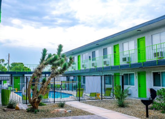 Fusion Las Vegas apartment complex 89119 with lime green doors flanking community pool and courtyard with desert landscaping and barbecue.
