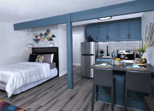Fusion Las Vegas studio apartments in Vegas bedroom and kitchen area with navy blue cabinets, stainless steel appliances, and two seater island.