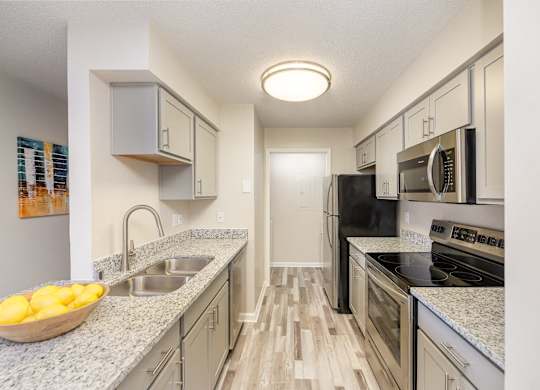 A kitchen equipped with stainless steel appliances, granite countertops, and hardwood-style flooring.