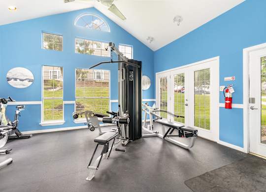 A gym with a variety of equipment including a treadmill, exercise bike, and weight machine.