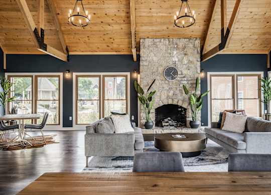 A gathering space with two grey couches, a fireplace, and large windows at Fairway Lakes.