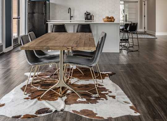 Fairway Lakes gathering area featuring a table surrounded by five chairs and hardwood-style flooring, next to a communal kitchen.