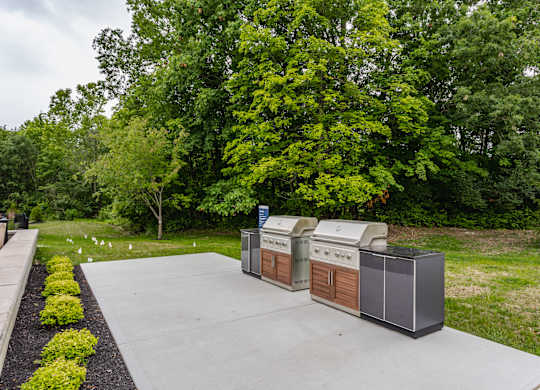 A large outdoor grill is in the middle of a concrete patio.