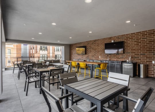 A private sky lounge at Madamore with tables and chairs, a brick wall, and two TV's.